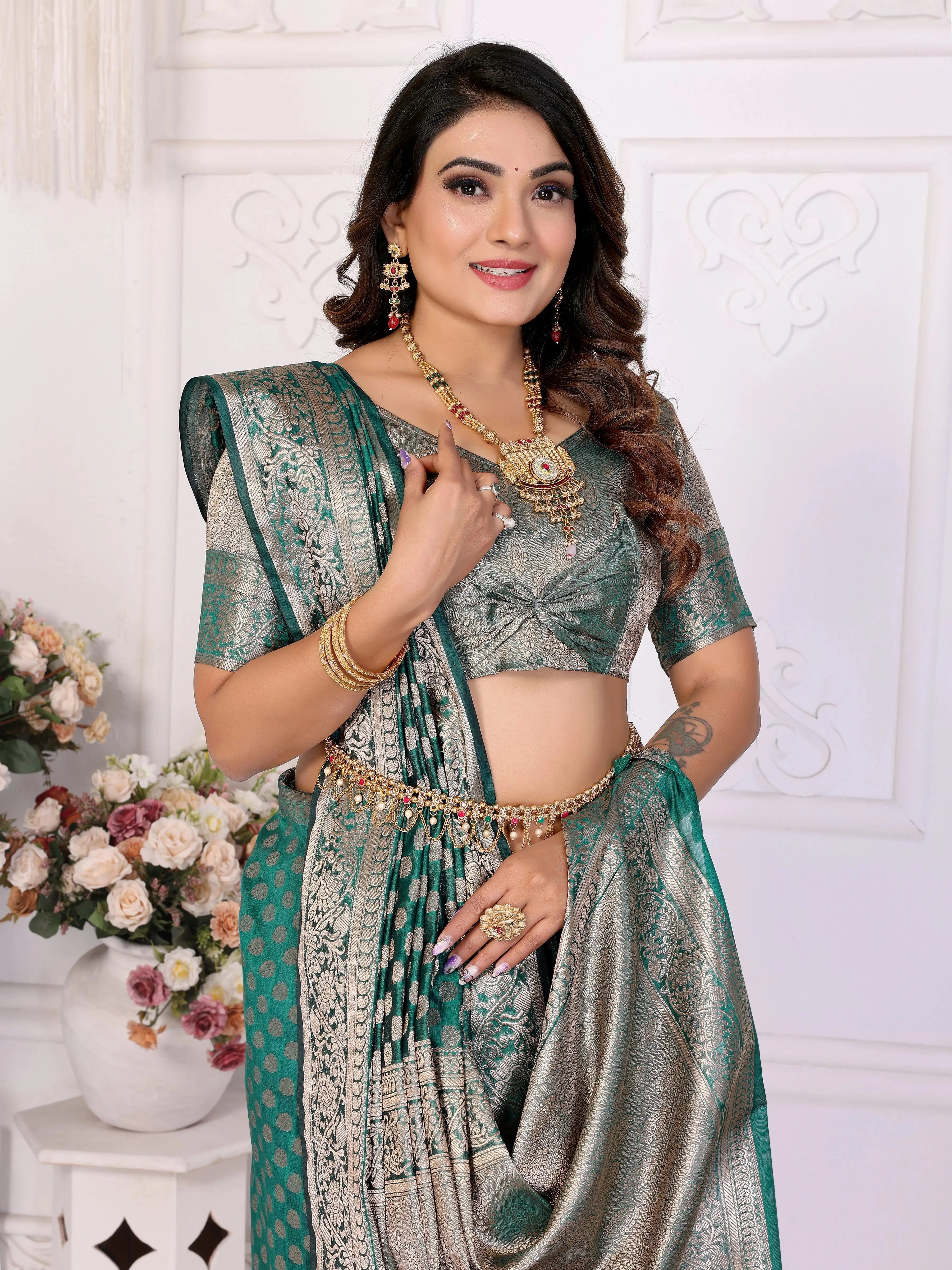 Woman in a traditional saree with jewelry against a white wall